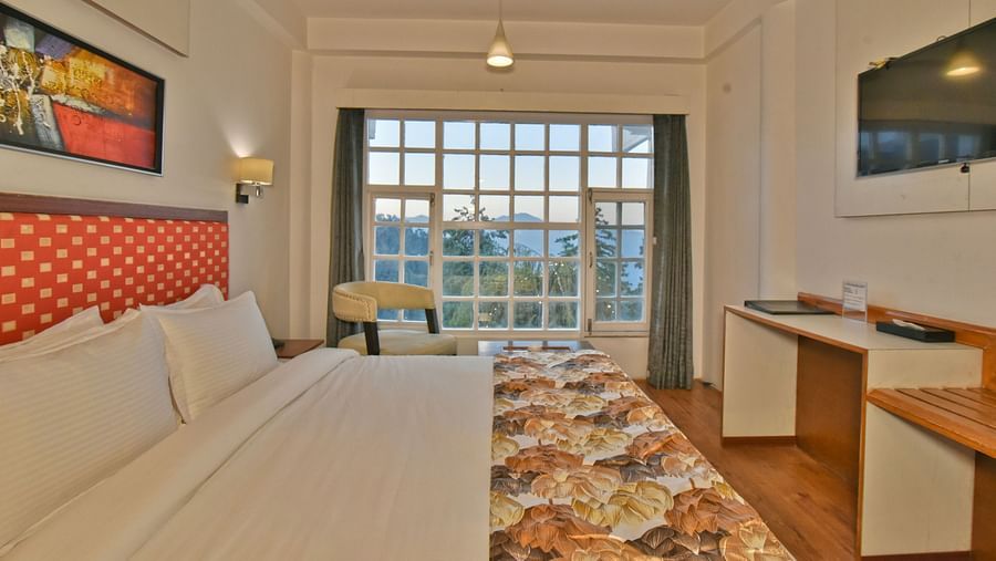 Bedroom with a wall-mounted television facing the bed at DLS Hillcrest Resort, Shimla.
